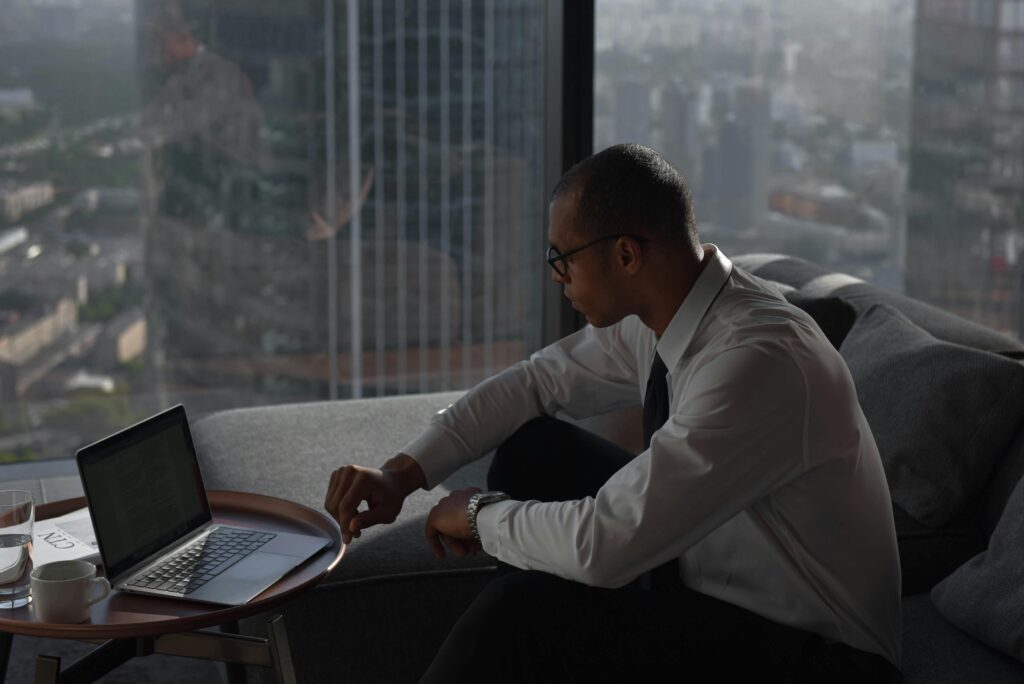 Businessman working on a laptop in a modern office setting with a panoramic city view.